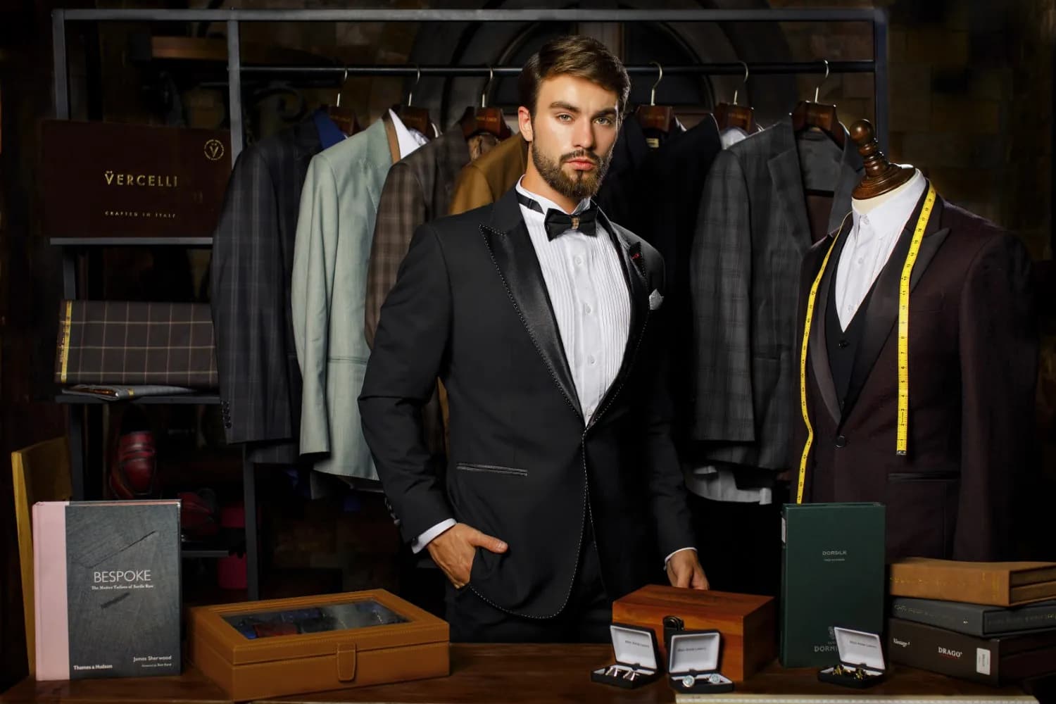 Nghệ nhân Mon Amie và khách mặc tuxedo trong showroom có kệ vải và sổ mẫu