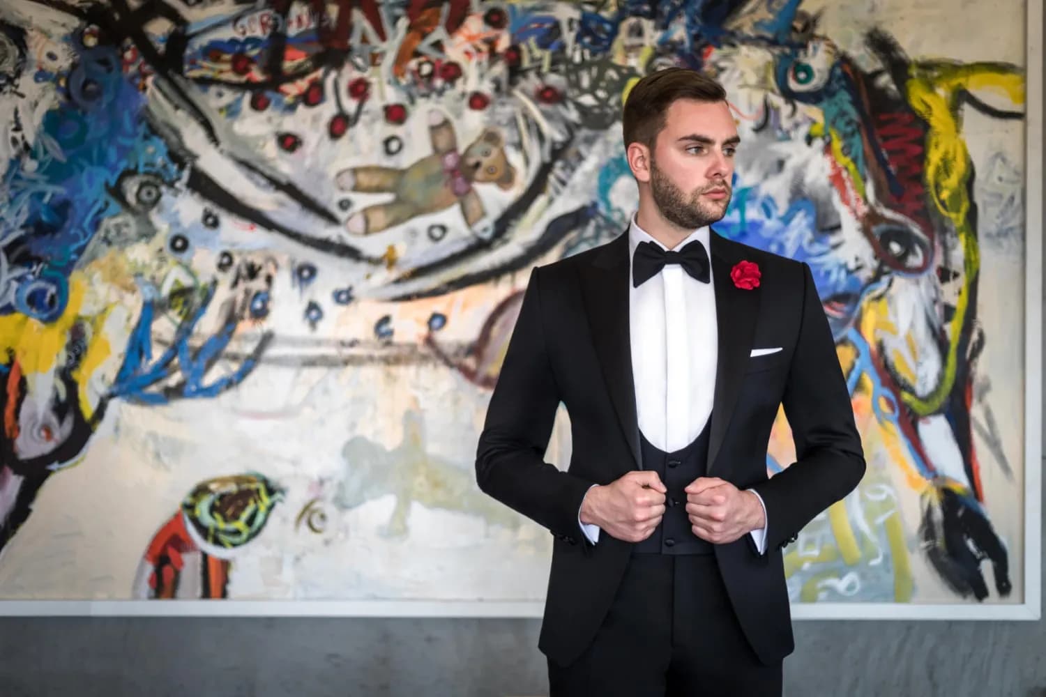 Quý ông mặc tuxedo đen trước bức tranh sơn dầu lớn