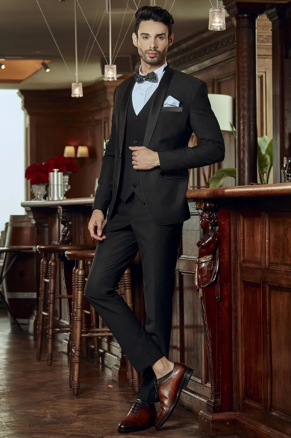 Quý ông mặc tuxedo ba mảnh đen bên quầy bar gỗ
